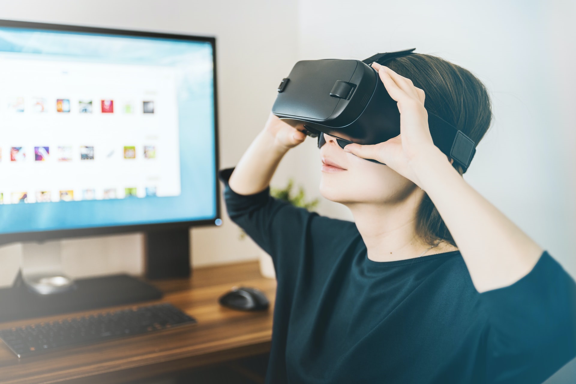 A woman using a VR headset in front of a computer