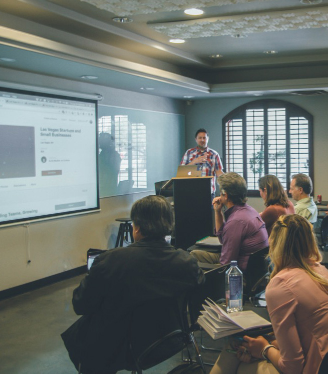 Instructor teaches in-person class with slides showing on a projector.